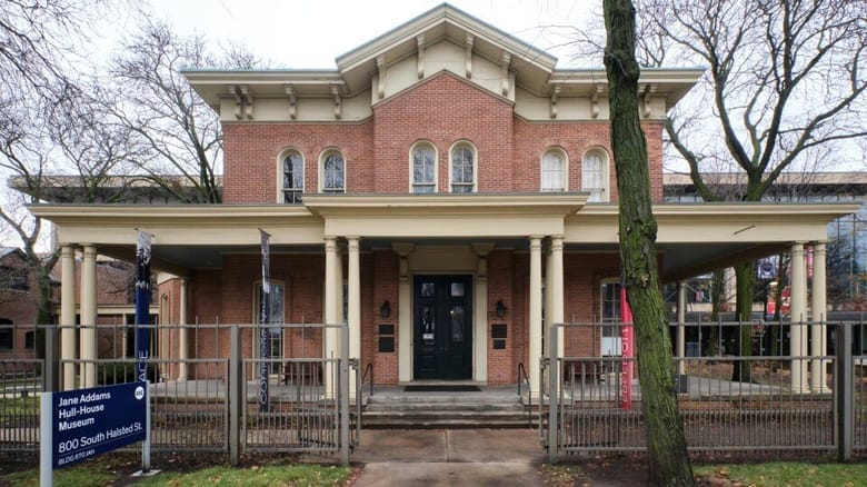 Large two story residential red brick building with cream colored trim and a large front porch.